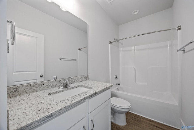 full bathroom with hardwood / wood-style flooring, vanity, washtub / shower combination, and toilet