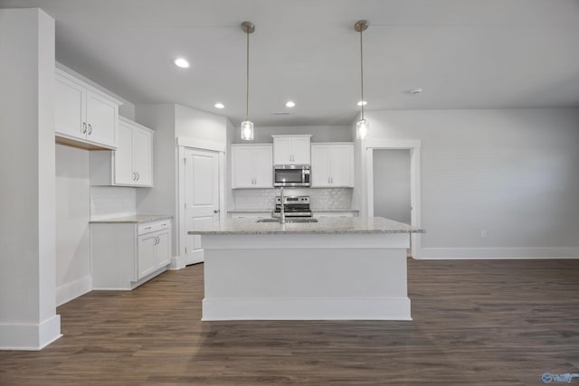 kitchen featuring a kitchen island with sink, hanging light fixtures, white cabinetry, and appliances with stainless steel finishes