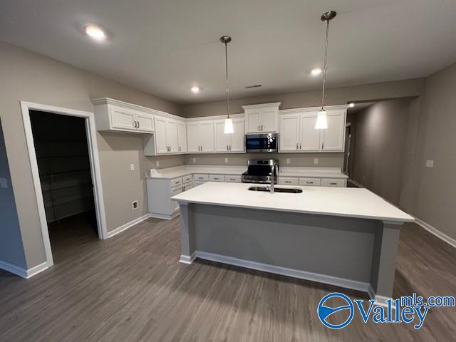 kitchen featuring white cabinetry, sink, hanging light fixtures, stainless steel appliances, and dark hardwood / wood-style flooring