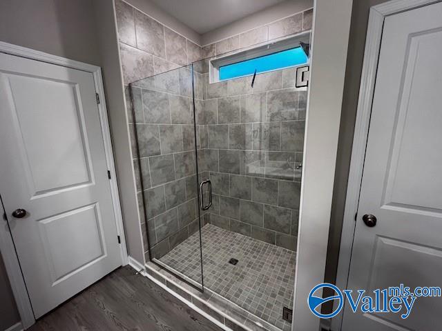 bathroom with wood-type flooring and a shower with shower door