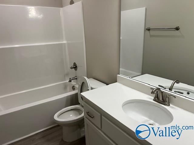 full bathroom featuring hardwood / wood-style flooring, vanity, toilet, and bathtub / shower combination