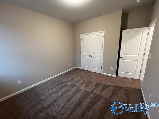 unfurnished bedroom featuring a closet and dark carpet