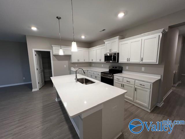 kitchen featuring white cabinetry, black electric range, a center island with sink, and sink