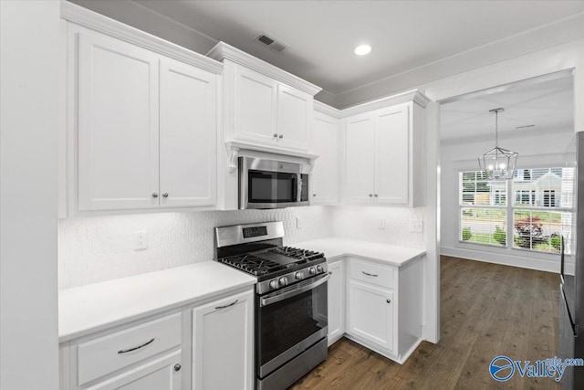 kitchen with white cabinets, appliances with stainless steel finishes, an inviting chandelier, and dark wood-type flooring