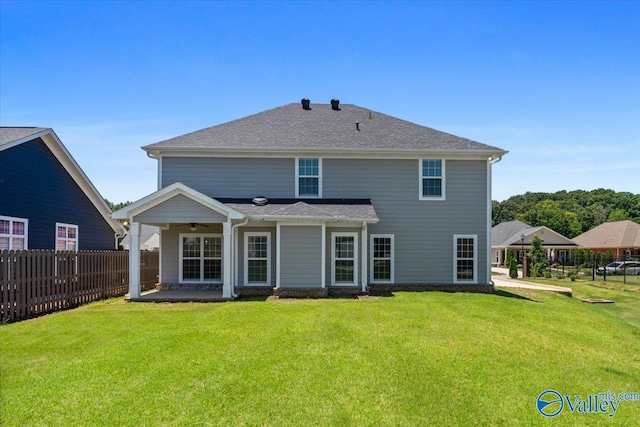 rear view of property with ceiling fan and a yard