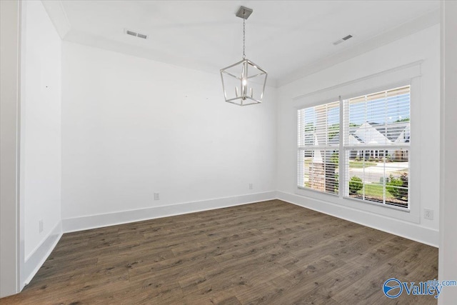 empty room with dark hardwood / wood-style flooring, an inviting chandelier, and crown molding