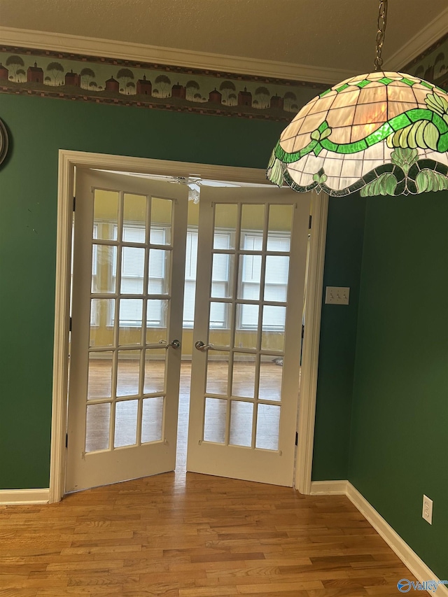 doorway with hardwood / wood-style floors, crown molding, and french doors