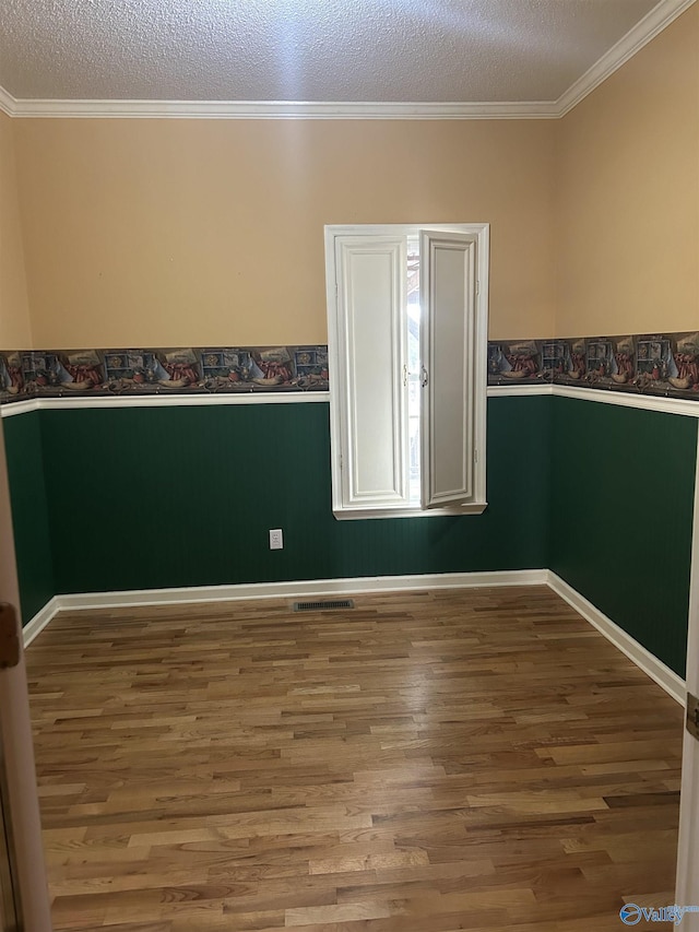 unfurnished room with crown molding, wood-type flooring, and a textured ceiling