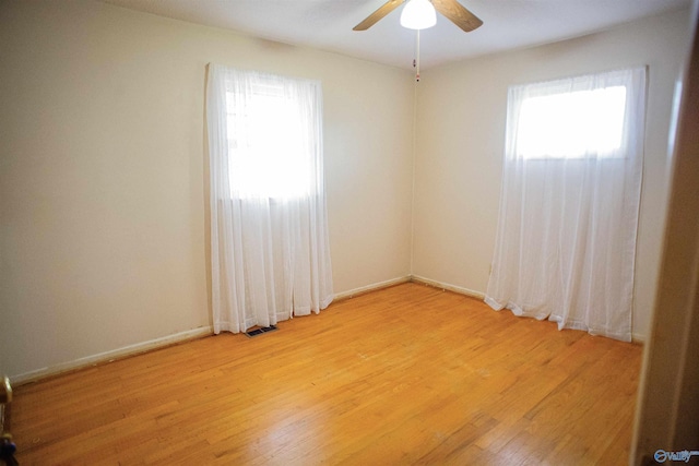 empty room with visible vents, a healthy amount of sunlight, light wood-type flooring, and ceiling fan