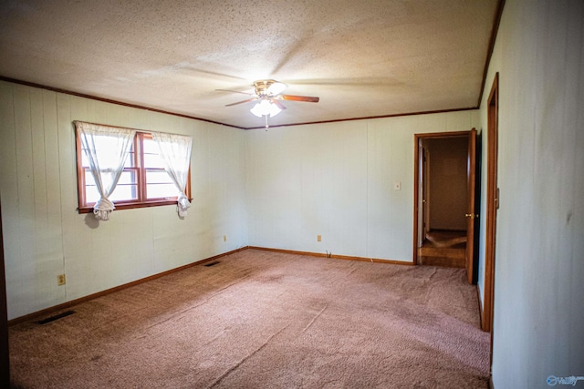 spare room with visible vents, carpet, crown molding, and a textured ceiling