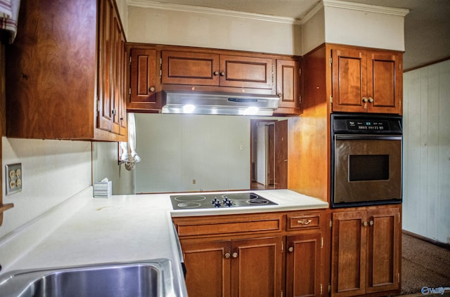 kitchen with oven, under cabinet range hood, brown cabinetry, light countertops, and black electric stovetop