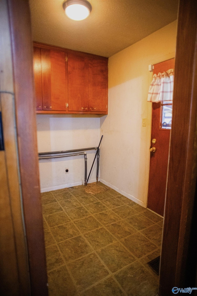 clothes washing area with visible vents, cabinet space, and baseboards