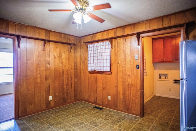 unfurnished room featuring tile patterned floors, ornamental molding, a ceiling fan, wooden walls, and baseboards