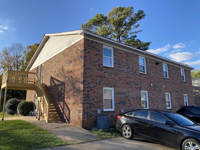 view of home's exterior with stairway, a deck, central AC, and brick siding