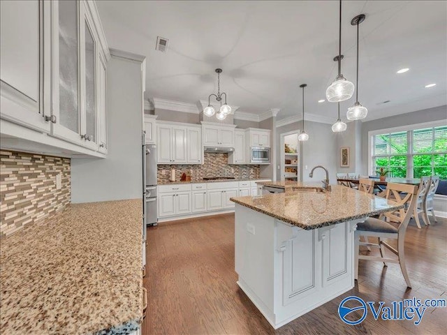 kitchen featuring white cabinets, appliances with stainless steel finishes, a breakfast bar, a sink, and backsplash
