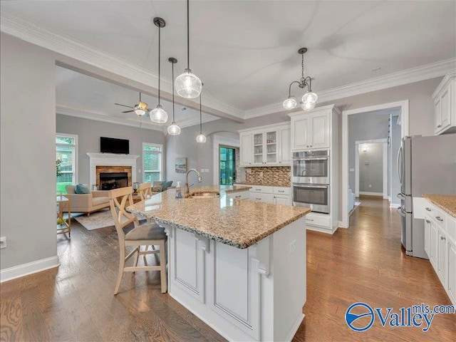 kitchen with a sink, open floor plan, white cabinetry, a ceiling fan, and appliances with stainless steel finishes