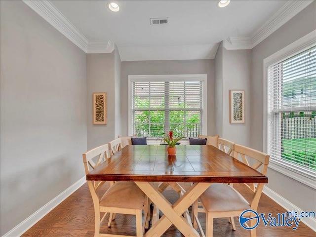 dining room featuring baseboards, ornamental molding, wood finished floors, and visible vents