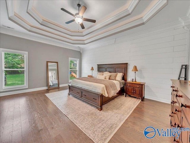 bedroom with baseboards, ornamental molding, dark wood finished floors, and a tray ceiling