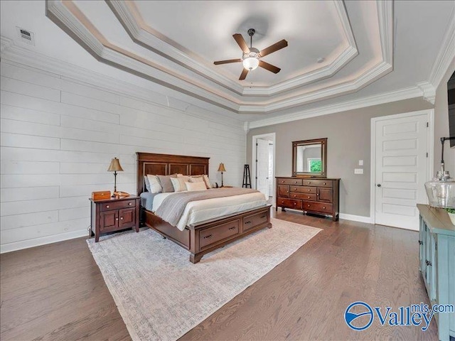 bedroom featuring crown molding, baseboards, ceiling fan, dark wood-style floors, and a tray ceiling
