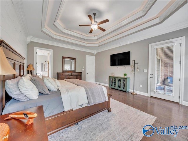 bedroom with ornamental molding, wood finished floors, access to exterior, baseboards, and a raised ceiling