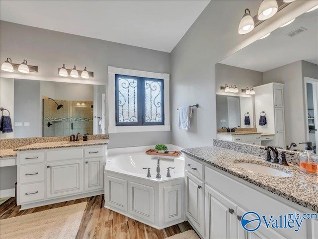bathroom with visible vents, a garden tub, wood finished floors, tiled shower, and a sink
