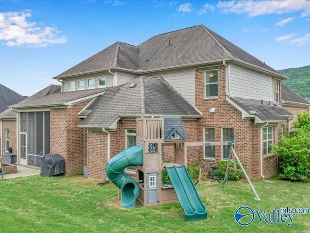 view of jungle gym with a sunroom and a lawn