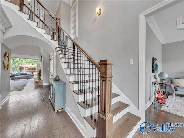 stairs featuring arched walkways, baseboards, ornamental molding, and wood finished floors