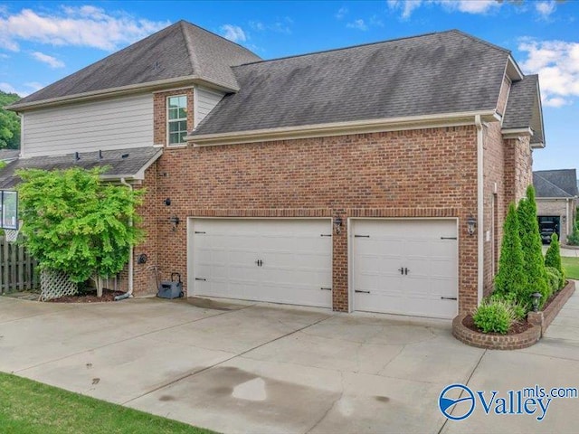 exterior space with concrete driveway, brick siding, roof with shingles, and a garage