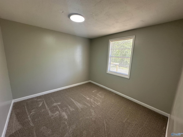 unfurnished room with carpet, baseboards, and a textured ceiling