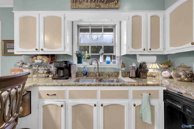 kitchen featuring light stone countertops, white cabinetry, black dishwasher, and sink