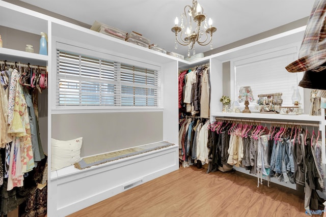 walk in closet featuring an inviting chandelier and hardwood / wood-style flooring