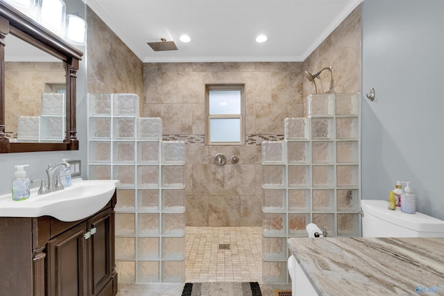 bathroom featuring toilet, vanity, tile patterned floors, crown molding, and a tile shower