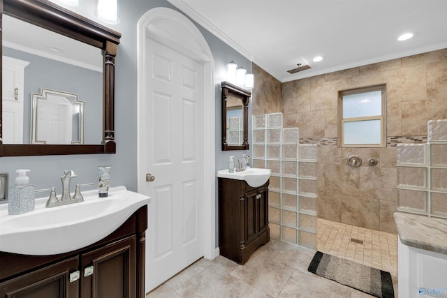 bathroom featuring a tile shower, crown molding, vanity, and tile patterned flooring