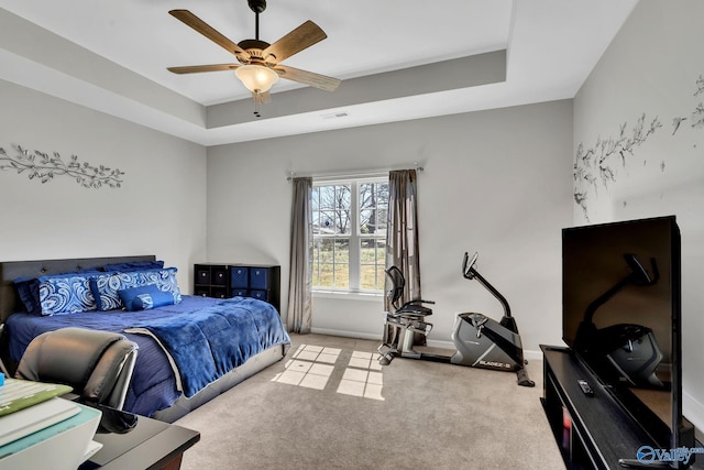 bedroom with visible vents, baseboards, a ceiling fan, a tray ceiling, and light colored carpet