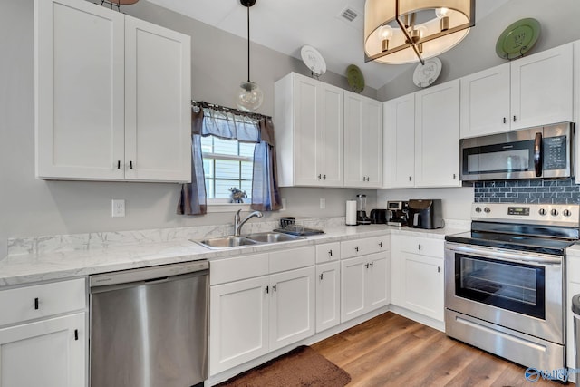 kitchen with a sink, wood finished floors, stainless steel appliances, visible vents, and white cabinets