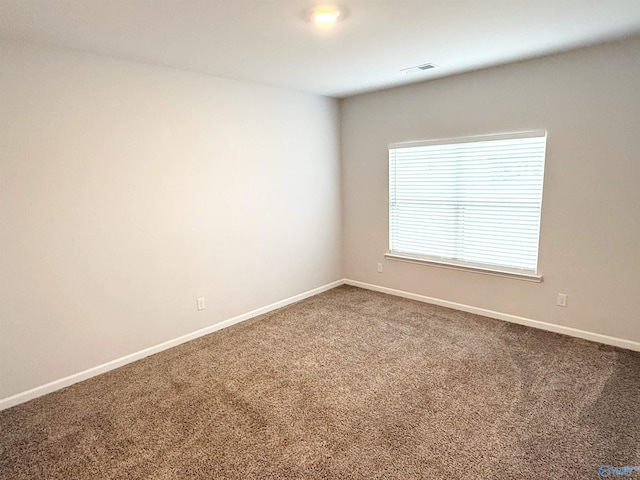 carpeted spare room featuring visible vents and baseboards