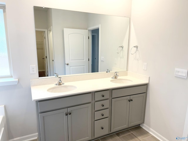 bathroom with a sink, baseboards, and double vanity