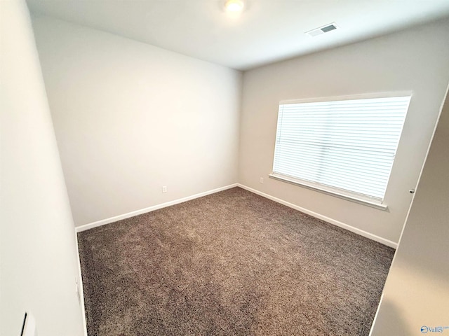 empty room with baseboards, visible vents, and dark carpet