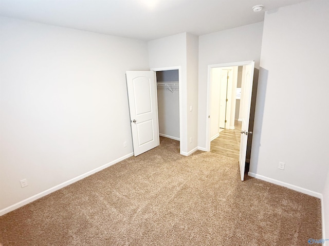 unfurnished bedroom featuring baseboards, a closet, and light carpet