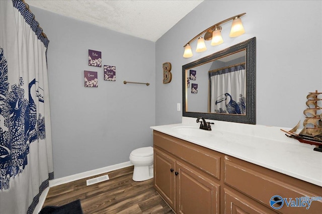 bathroom featuring wood-type flooring, vanity, a textured ceiling, and toilet