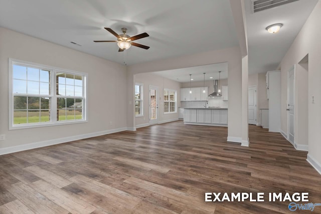 unfurnished living room featuring sink, hardwood / wood-style floors, ceiling fan, and plenty of natural light