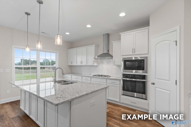 kitchen with wall chimney exhaust hood, sink, white cabinets, and stainless steel appliances