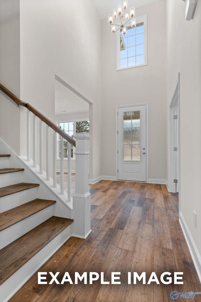 entrance foyer featuring a wealth of natural light, an inviting chandelier, hardwood / wood-style flooring, and a towering ceiling