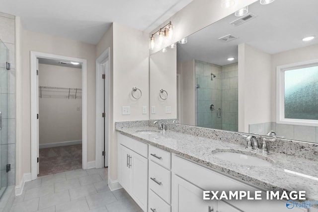 bathroom featuring a shower with door, vanity, and tile patterned flooring