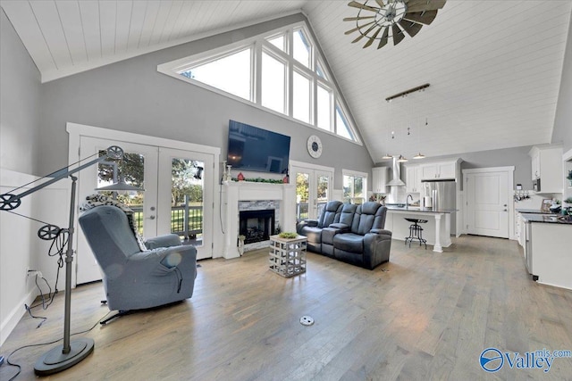 living room featuring ceiling fan, light hardwood / wood-style floors, high vaulted ceiling, and french doors