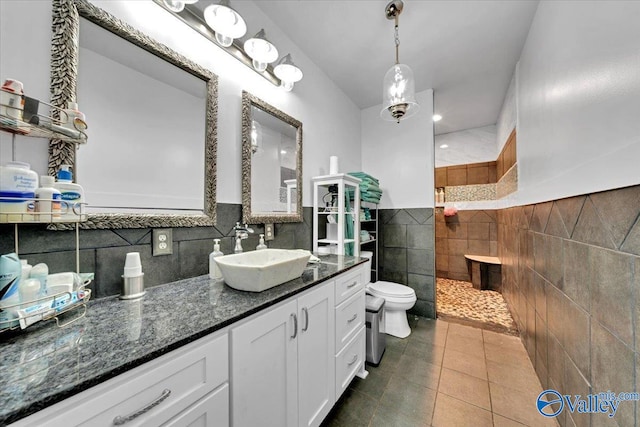 bathroom featuring walk in shower, tile patterned flooring, toilet, vanity, and tile walls