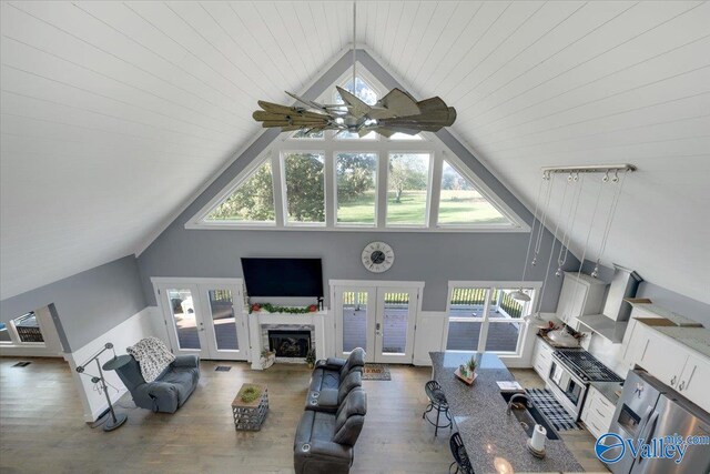 living room with hardwood / wood-style floors, high vaulted ceiling, plenty of natural light, and ceiling fan