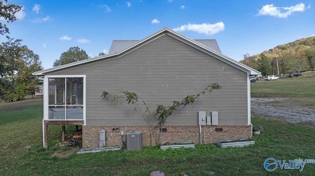 view of home's exterior with a sunroom, central air condition unit, and a lawn