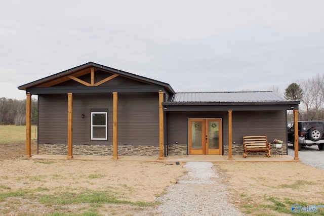 view of front of home with stone siding, french doors, and metal roof