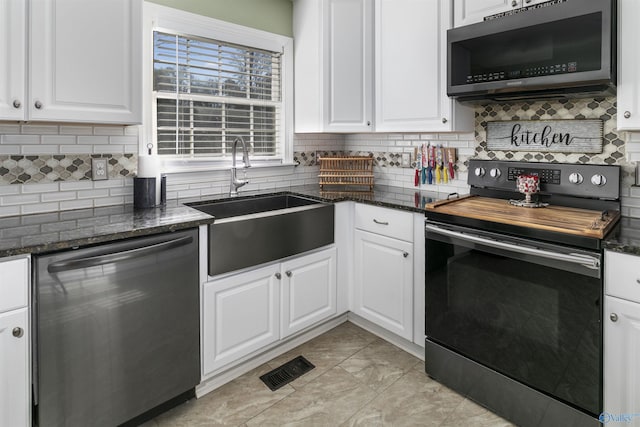 kitchen featuring white cabinetry, sink, dark stone countertops, decorative backsplash, and appliances with stainless steel finishes